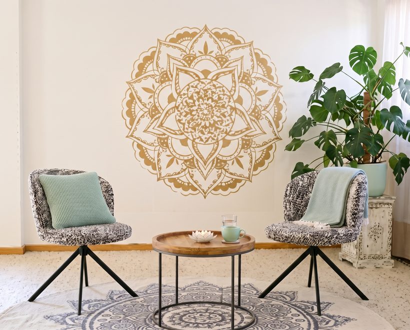 Sitzungsraum von Lichtimpuls im Kaivalya Studio in Wil SG: zwei Drehstühle am runden Holztisch, goldenes Mandala an der Wand und Monstera – hier finden die Logosynthese-Einzelsitzungen statt